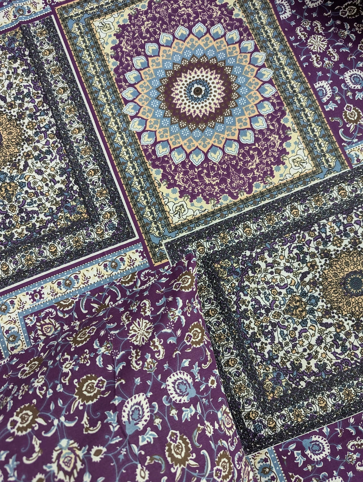 A close-up of a patterned fabric featuring traditional Persian-style rugs with intricate medallion and floral motifs in purple, navy, beige, and gold.