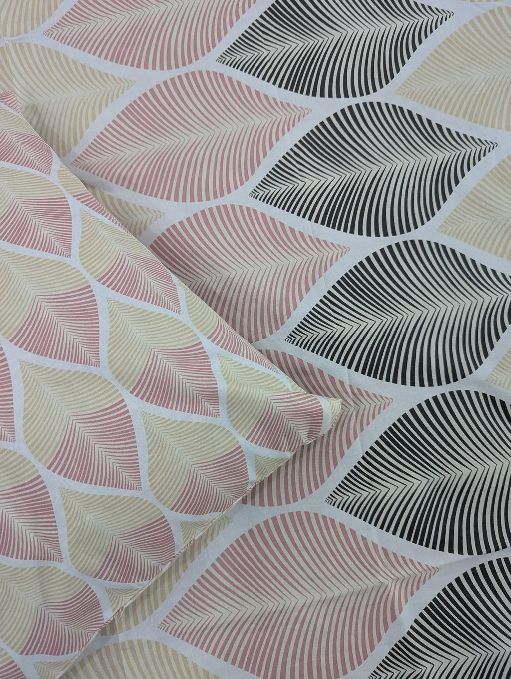 A close-up of patterned fabric with a repeating leaf design in blush pink, cream, and black on a white base, with a folded section showing the texture and color mix.