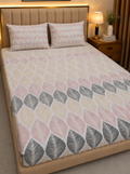 A bed dressed in a patterned duvet cover and two matching pillowcases, shown in a styled bedroom with a padded beige headboard, bedside lamp, and nightstand.