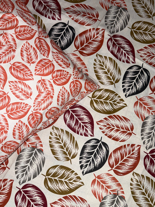 A close-up of a patterned fabric featuring a repeating design of stylized leaves in red, burgundy, olive green, and charcoal gray on a warm off-white background.