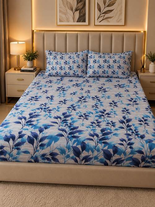 A neatly made bed in a modern bedroom setting, featuring a white bedding set with a blue floral and leaf pattern, including a duvet cover and two matching pillowcases.